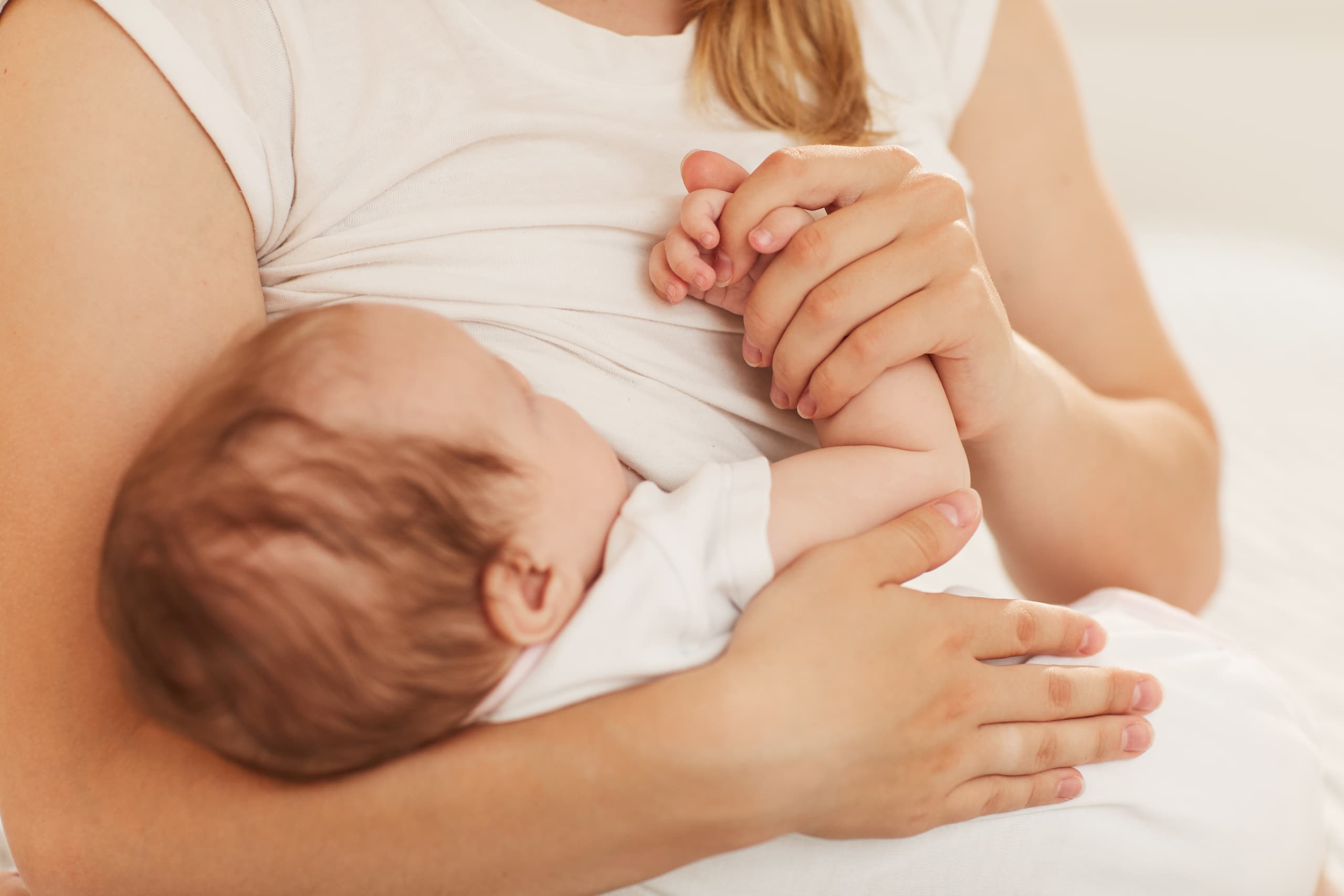 Mor holder en nyfødt baby inntil brystet